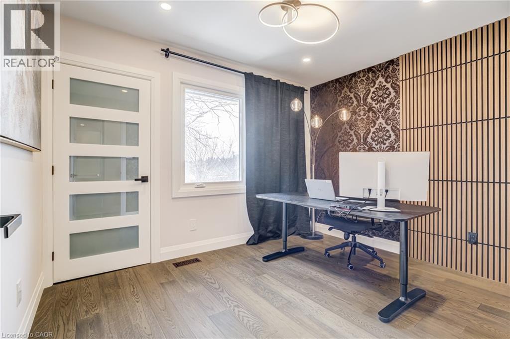 Contemporary room featuring wood-finish flooring and a white door with frosted glass panels - 1320 Monmouth Drive, Burlington, ON