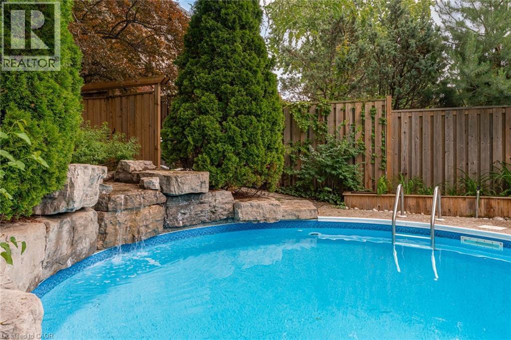 Private backyard featuring a swimming pool with a rock waterfall feature - 1320 Monmouth Drive, Burlington, ON