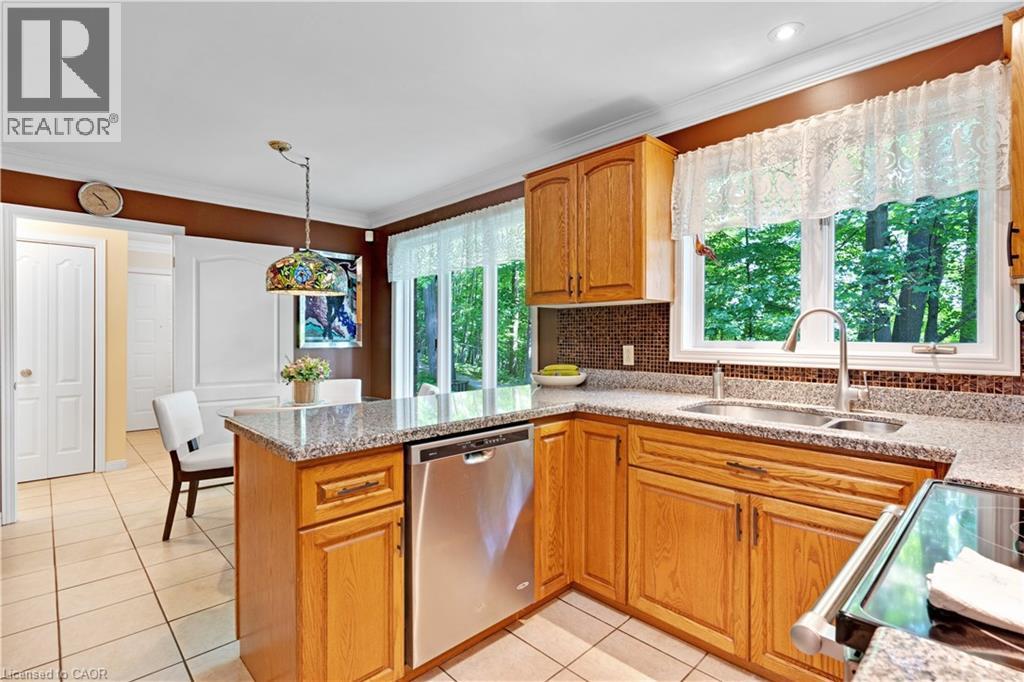 Kitchen featuring wood cabinetry, granite countertops, tile flooring, a stainless steel dishwasher, and a double-basin stainless steel sink with a gooseneck faucet - 110 Grand Ridge Drive, Cambridge, ON