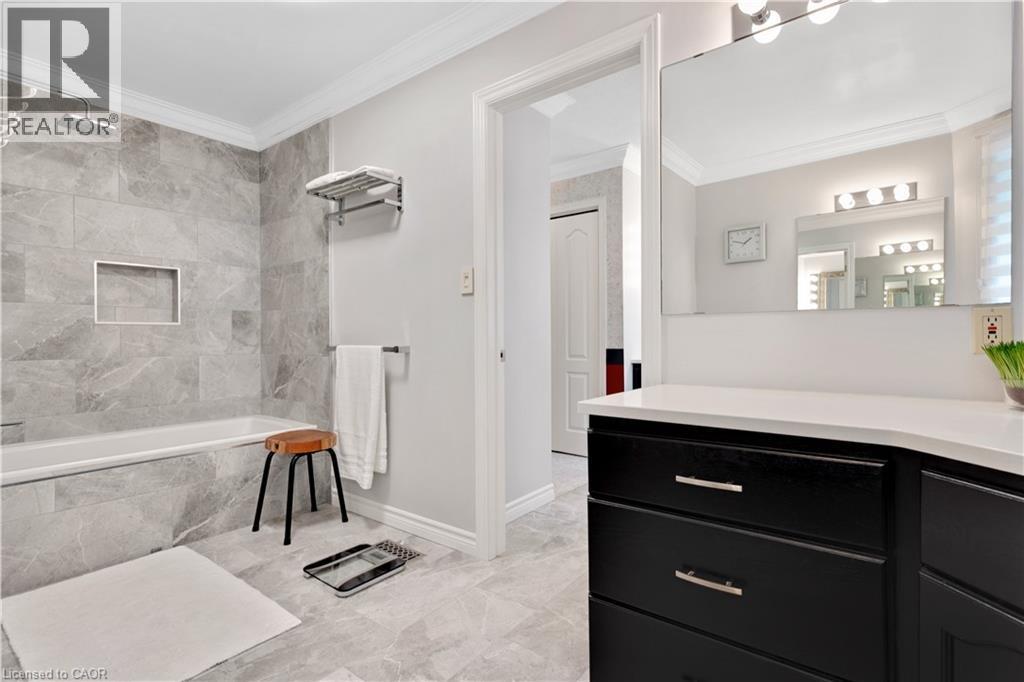 Bathroom featuring a shower-tub combination with gray large-format tile surround, recessed niche, and rain showerhead - 110 Grand Ridge Drive, Cambridge, ON