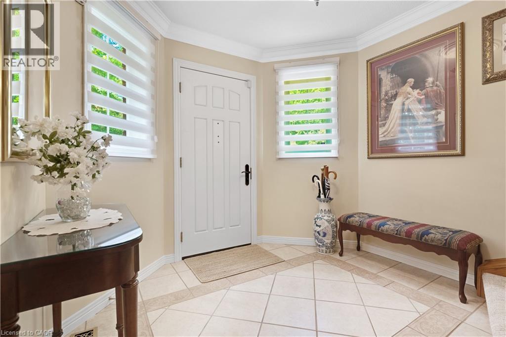 Foyer featuring a paneled entry door, crown molding, and complementary two-tone tile flooring - 110 Grand Ridge Drive, Cambridge, ON