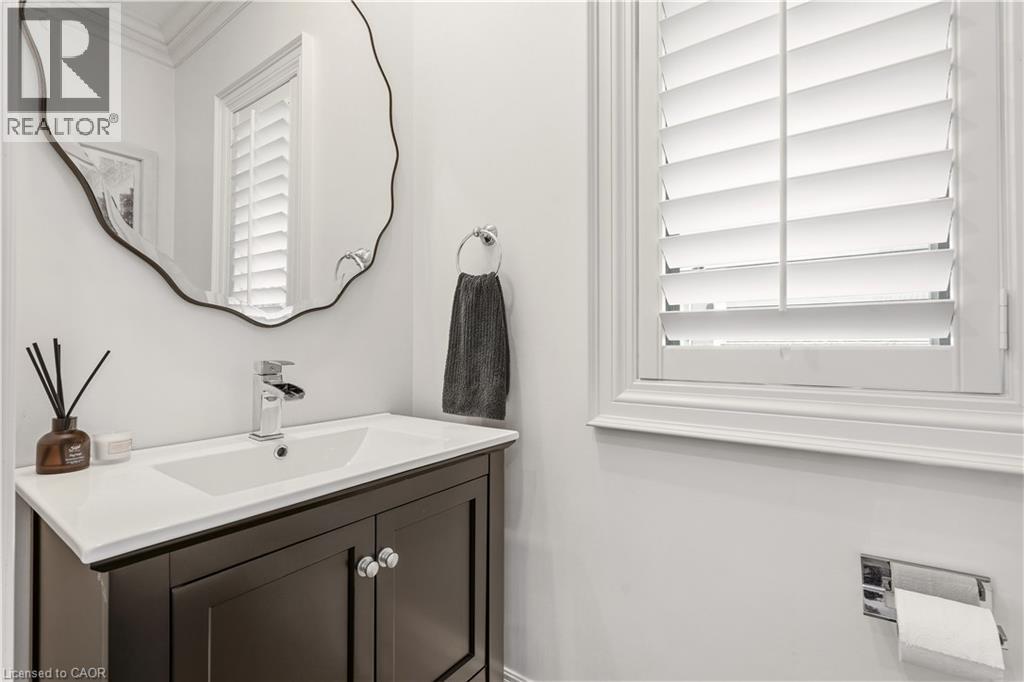 Dark wood vanity with a white integrated sink, polished chrome faucet, and an organic-shaped mirror - 336 Newbold Court, Burlington, ON
