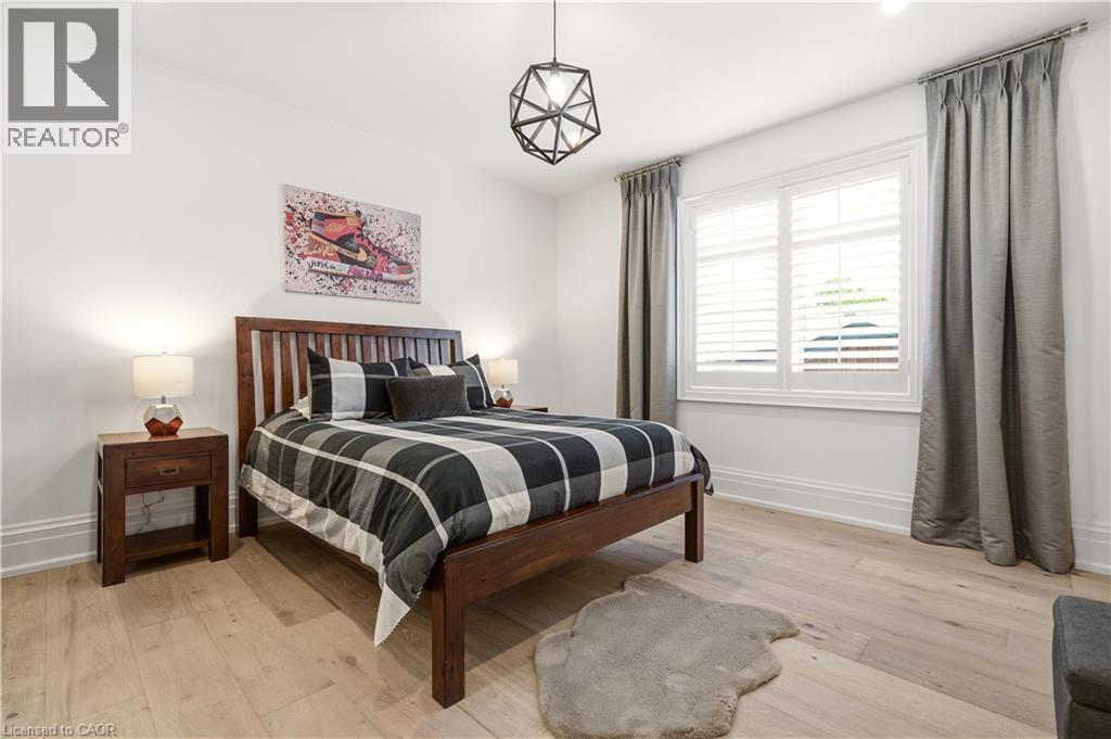 Bedroom featuring light wood-finish flooring, white walls, and a window with plantation shutters - 336 Newbold Court, Burlington, ON