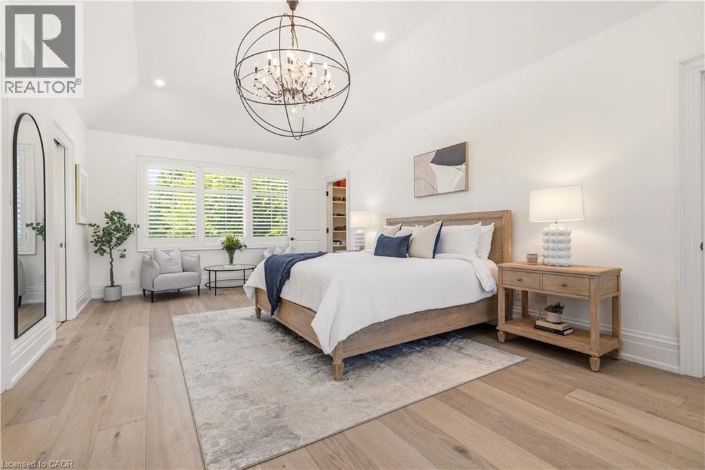 Spacious room featuring vaulted ceilings, wide plank wood-finish flooring, a contemporary chandelier, large windows with plantation shutters, and a built-in closet with shelving - 336 Newbold Court, Burlington, ON