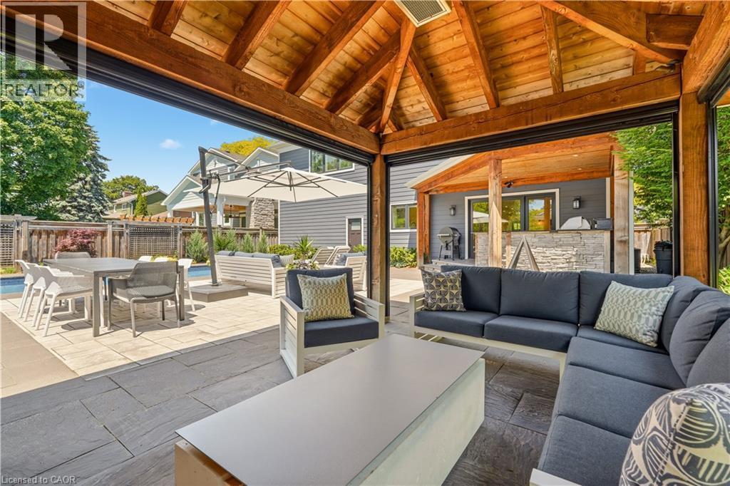 Expansive outdoor living area featuring a vaulted wood-beam ceiling, stone-look tile flooring, and a built-in outdoor kitchen with stone detailing - 336 Newbold Court, Burlington, ON