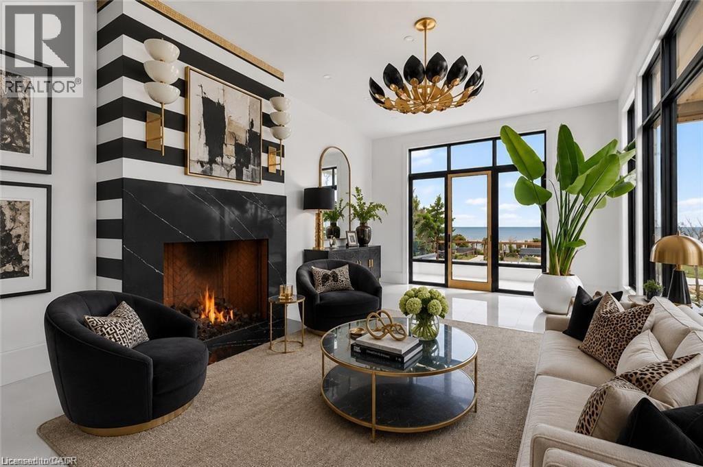 Contemporary living area featuring a striking black and white striped fireplace with a black stone surround, large format tile flooring, and expansive windows offering a water view - 711 Beach Boulevard, Hamilton, ON