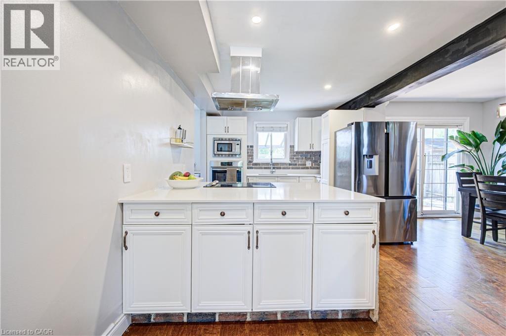 Kitchen featuring a large central island with white cabinetry, stainless steel appliances, recessed lighting, and wood-finish flooring - 154 Grand Avenue S, Cambridge, ON
