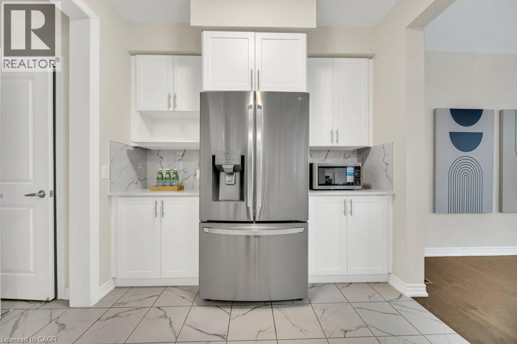 Kitchen with appliances with stainless steel finishes, white cabinetry, and tasteful backsplash - 285 Broadacre Drive, Kitchener, ON