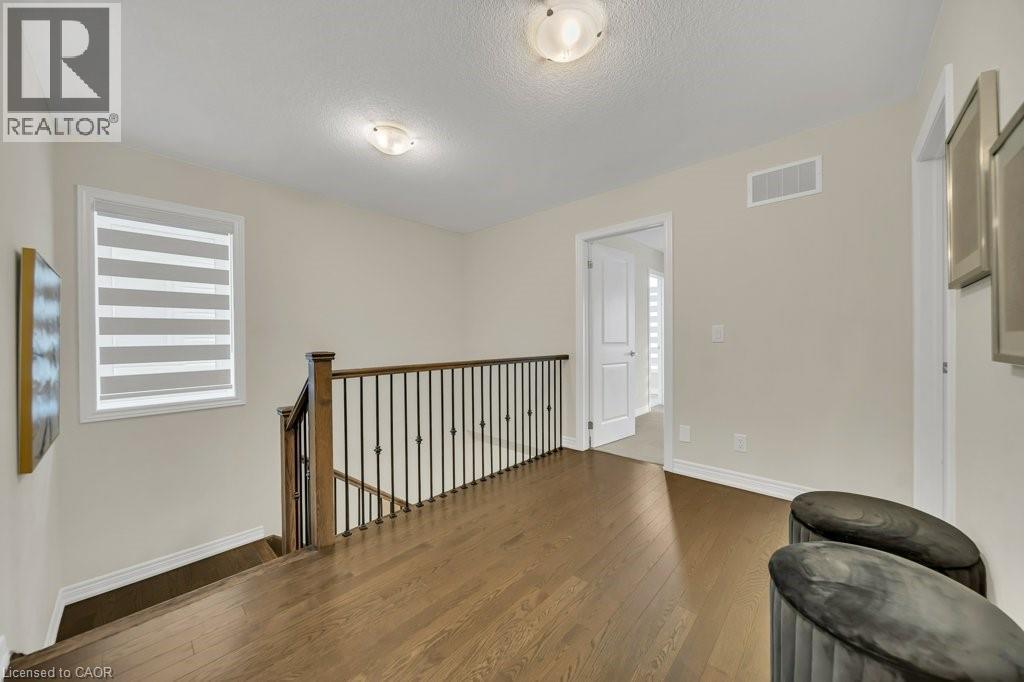 Unfurnished room with wood finished floors, an upstairs landing, and a textured ceiling - 285 Broadacre Drive, Kitchener, ON