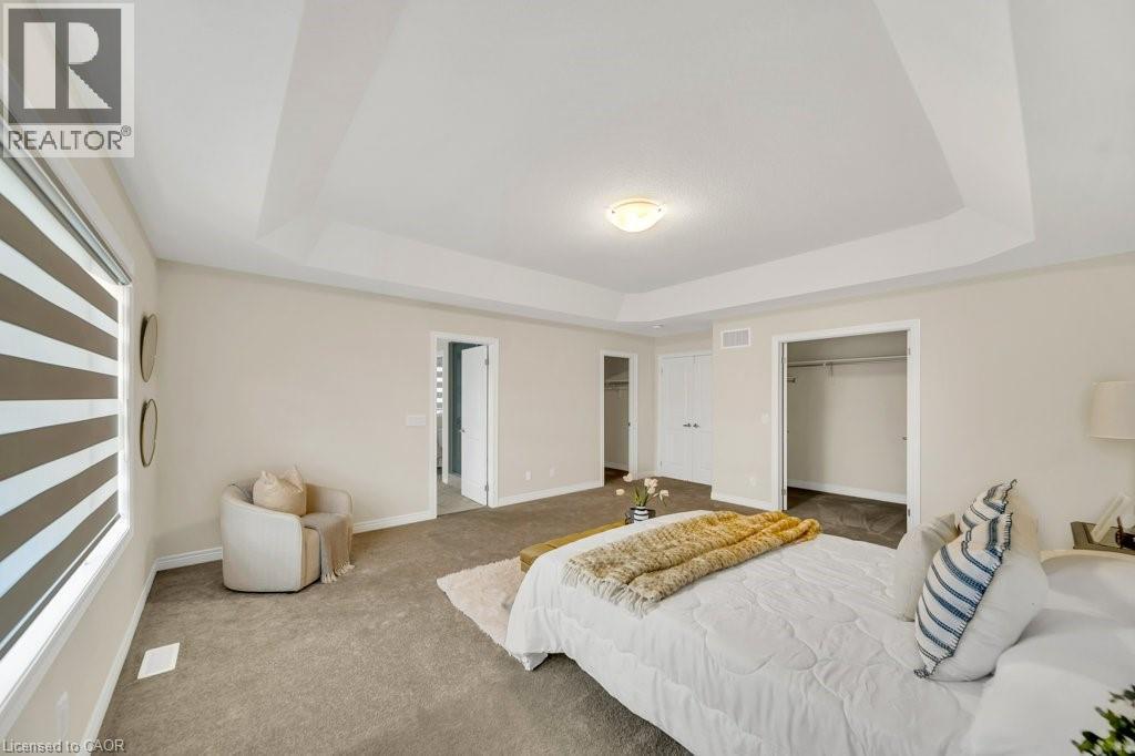 Carpeted bedroom featuring a raised ceiling and a walk in closet - 285 Broadacre Drive, Kitchener, ON