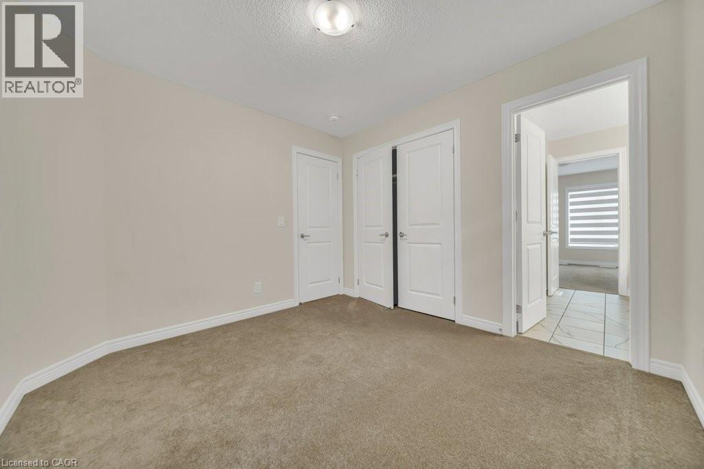 Unfurnished bedroom with light colored carpet, a textured ceiling, and a closet - 285 Broadacre Drive, Kitchener, ON