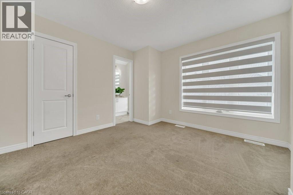 Empty room featuring light carpet and healthy amount of natural light - 285 Broadacre Drive, Kitchener, ON