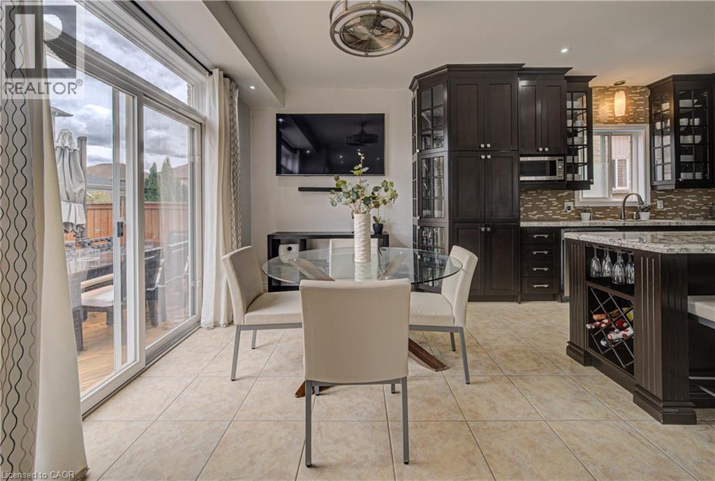 Kitchen and dining area featuring ceramic tile flooring, dark wood cabinetry with glass-front accents, and a built-in wine rack - 37 Davinci Boulevard, Hamilton, ON