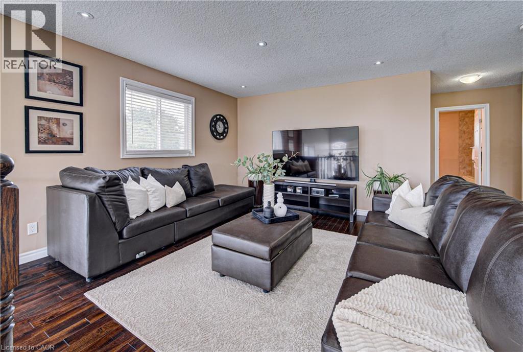 Spacious living area featuring wood-finish flooring, recessed lighting, and ample natural light from a window with blinds - 37 Davinci Boulevard, Hamilton, ON