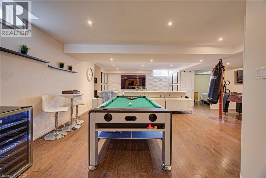 Spacious entertainment room featuring wood-finish flooring, recessed lighting, and a built-in beverage cooler - 37 Davinci Boulevard, Hamilton, ON