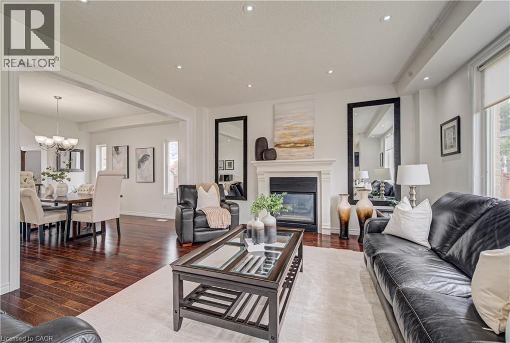 Bright living area featuring recessed lighting, a fireplace with a white mantel, and rich wood-finish flooring - 37 Davinci Boulevard, Hamilton, ON