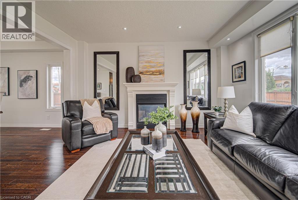 Living area featuring a fireplace with a white mantel, recessed lighting, wood-finish flooring, and multiple windows - 37 Davinci Boulevard, Hamilton, ON