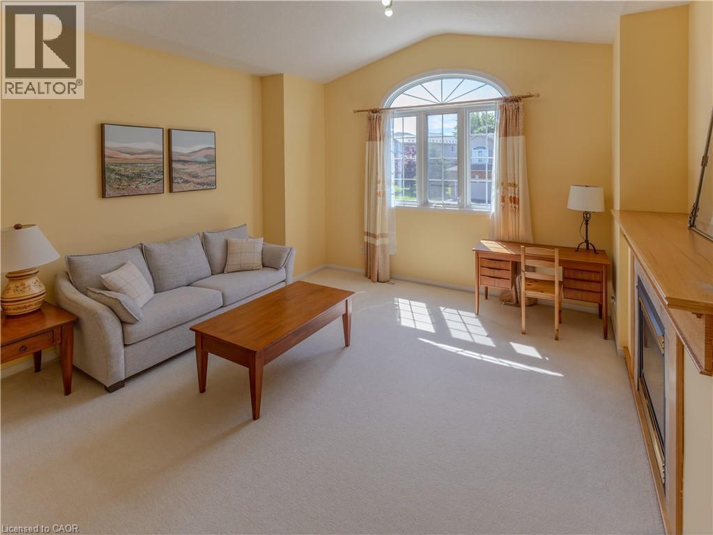 Living area featuring carpet flooring, an arched transom window, vaulted ceiling, and a built-in media console - 212 Sleaford Street, Waterloo, ON