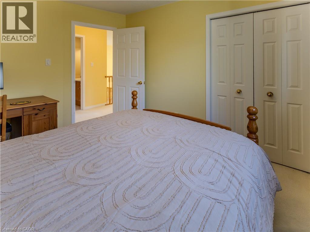 Bright interior featuring light yellow walls, white bi-fold closet doors with brass hardware, and a wood-finish desk - 212 Sleaford Street, Waterloo, ON