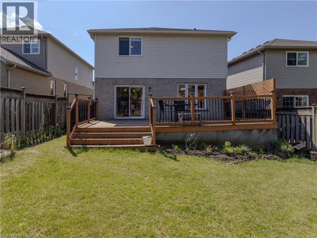 Expansive rear yard featuring a large wood-finish deck with black metal balusters, privacy lattice, and direct access to the interior via sliding glass doors - 212 Sleaford Street, Waterloo, ON