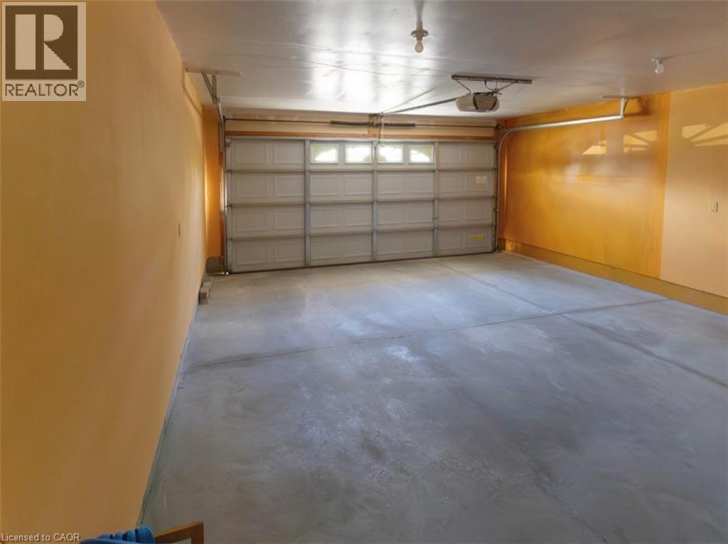 Spacious garage featuring a concrete floor, overhead lighting, and an automatic garage door opener - 212 Sleaford Street, Waterloo, ON