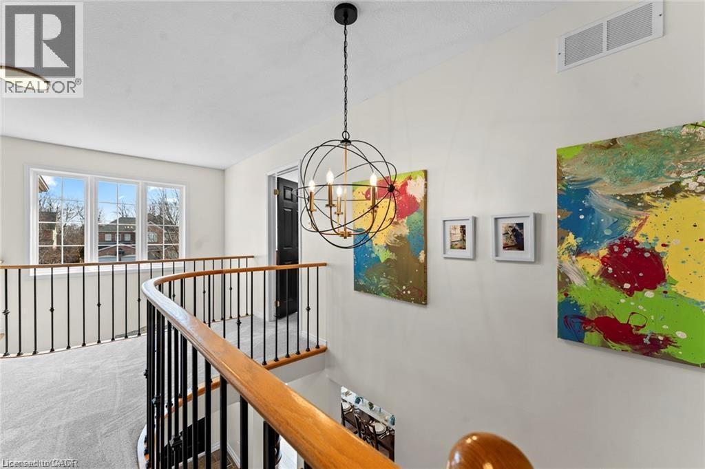 Curved staircase with black metal spindles and a wood-finish handrail - 26 Shadyridge Place, Kitchener, ON