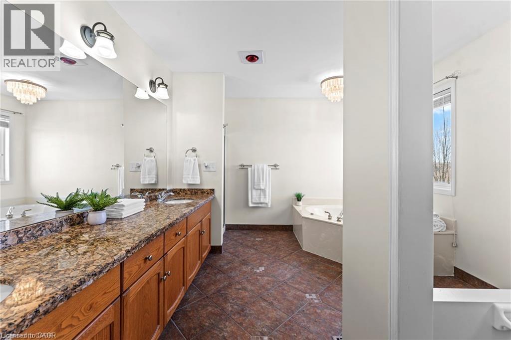 Spacious bathroom featuring an extended wood-finish vanity with dual sinks, granite countertop, and ample storage cabinetry - 26 Shadyridge Place, Kitchener, ON