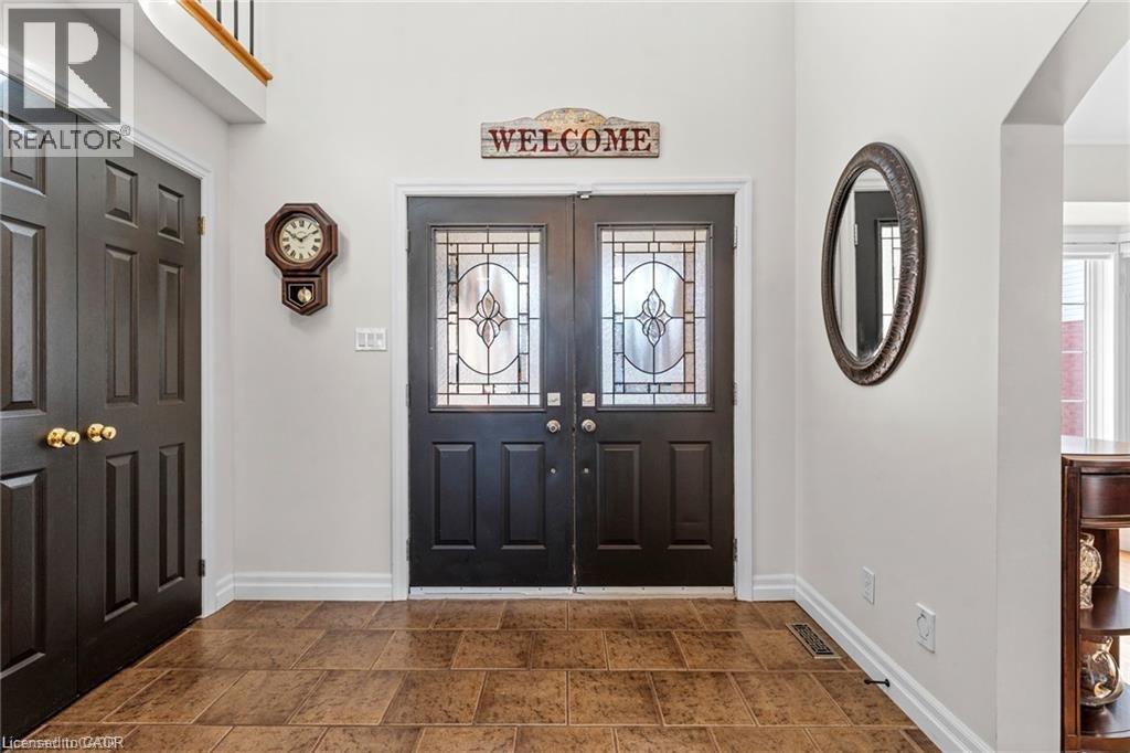 Foyer featuring dual entry doors with decorative glass inserts, ceramic tile flooring, and a paneled closet door - 26 Shadyridge Place, Kitchener, ON