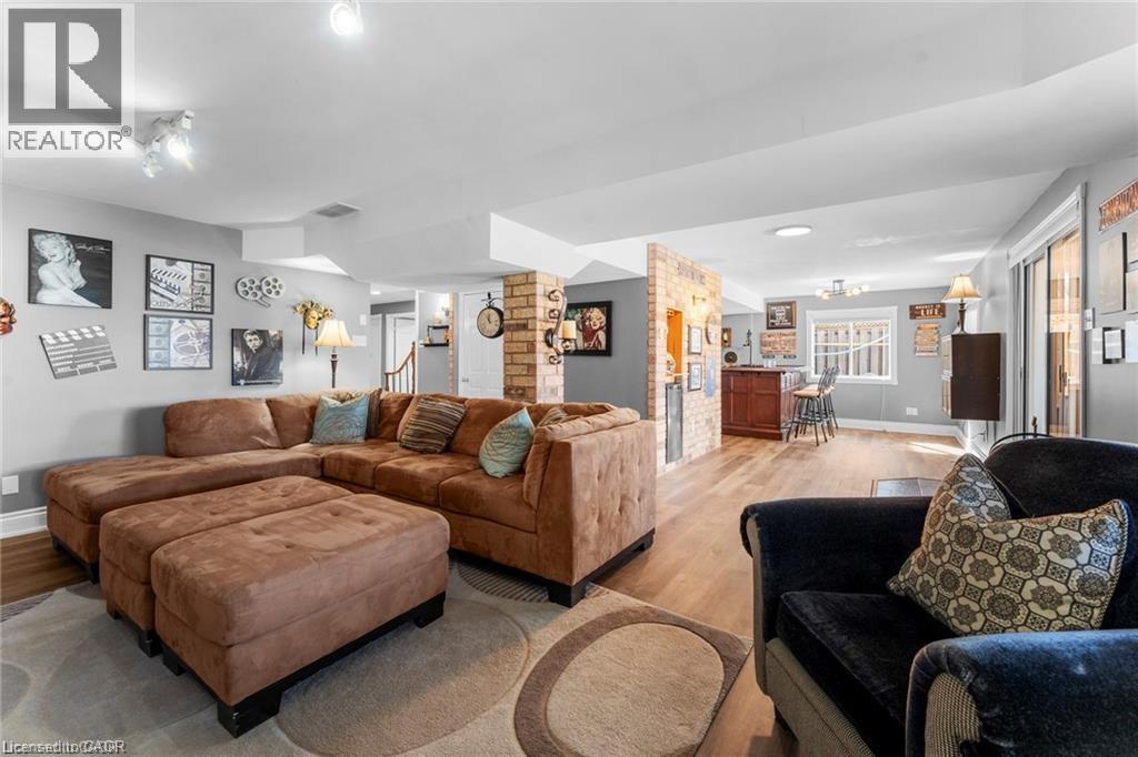 Spacious lower-level entertainment area featuring wood-finish flooring, recessed lighting, track lighting, and a built-in bar with brick-style accents - 26 Shadyridge Place, Kitchener, ON
