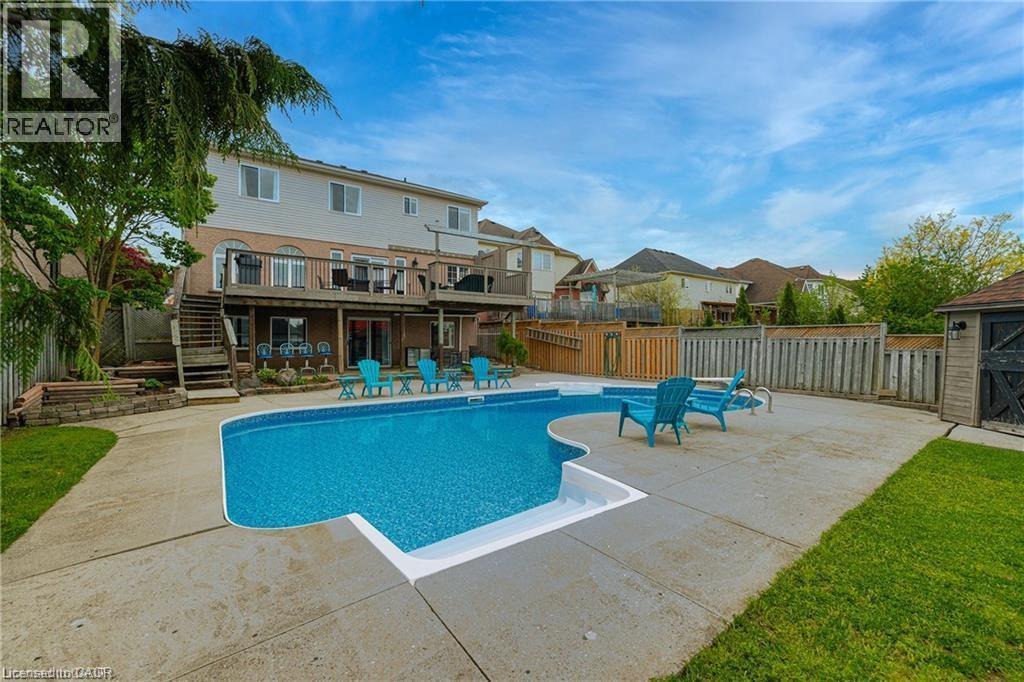 Expansive backyard featuring a large in-ground swimming pool with concrete surround, two-story rear deck with stairs, a shed, and mature perimeter fencing - 26 Shadyridge Place, Kitchener, ON