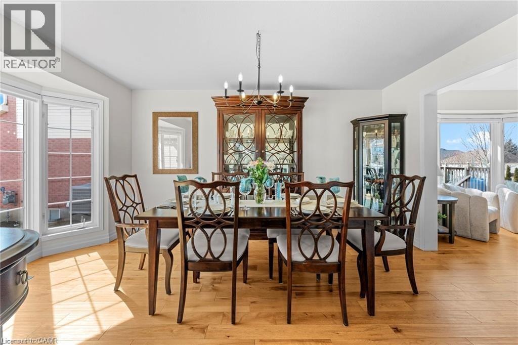 Bright dining area featuring light wood-finish flooring, a bay window with white trim, and a built-in display cabinet - 26 Shadyridge Place, Kitchener, ON