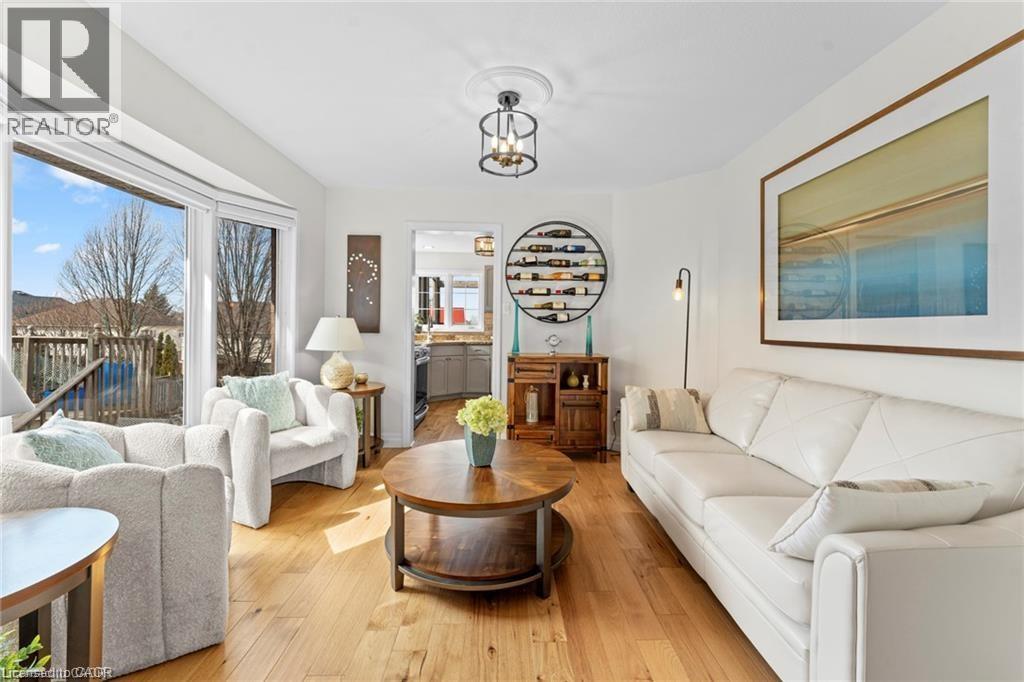 Living area featuring wood-finish flooring, a bay window, a recessed ceiling, and a prominent archway - 26 Shadyridge Place, Kitchener, ON