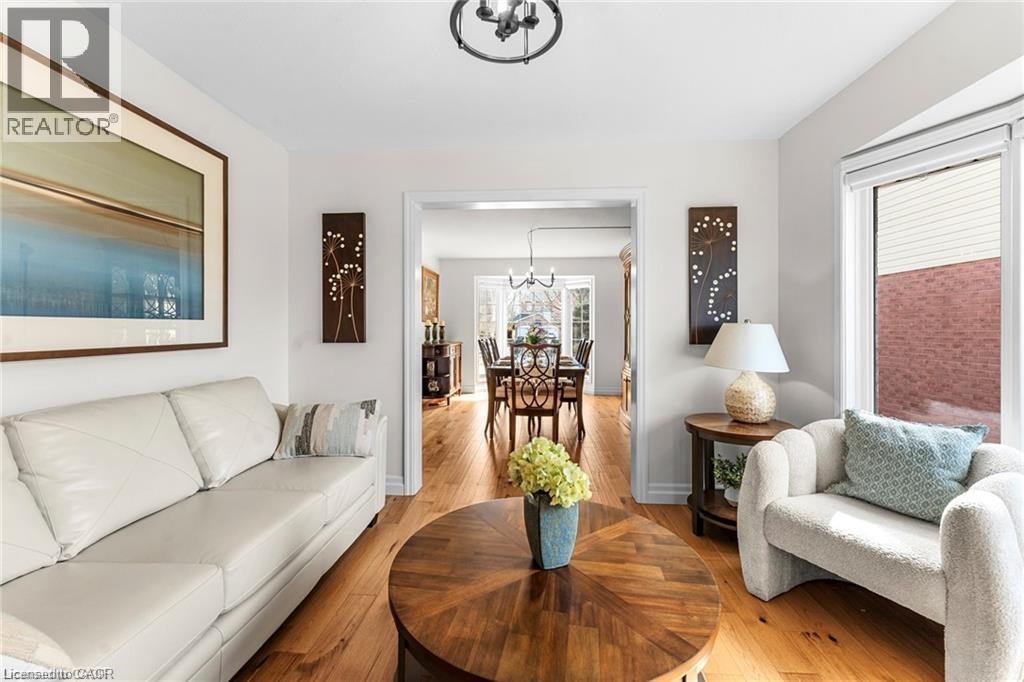 Bright living area featuring wood-finish flooring and a contemporary chandelier - 26 Shadyridge Place, Kitchener, ON