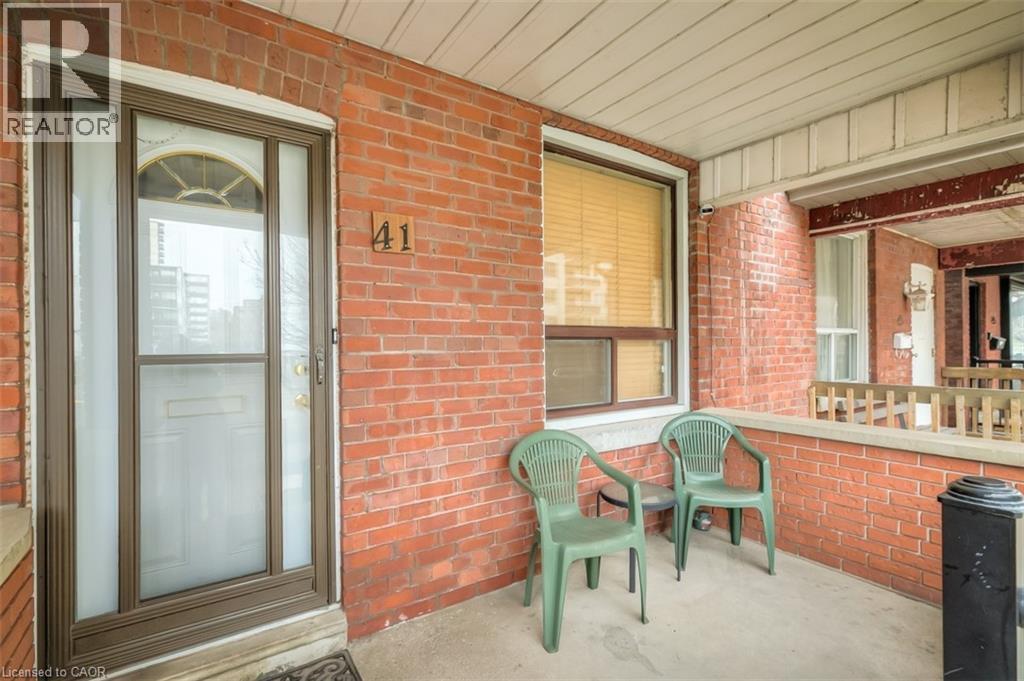 Brick facade with a covered porch featuring a storm door, an arched transom window, and an adjacent window with horizontal blinds - 41 Springhurst Avenue, Toronto, ON