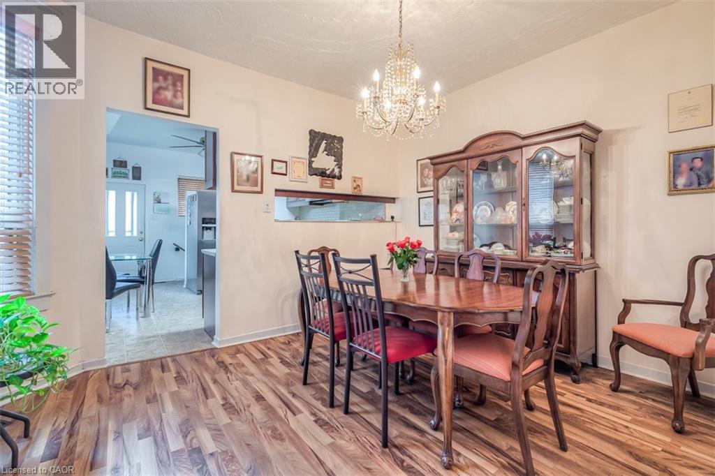 Dining area featuring wood-finish flooring, a crystal chandelier, and a pass-through window to the adjacent kitchen - 41 Springhurst Avenue, Toronto, ON