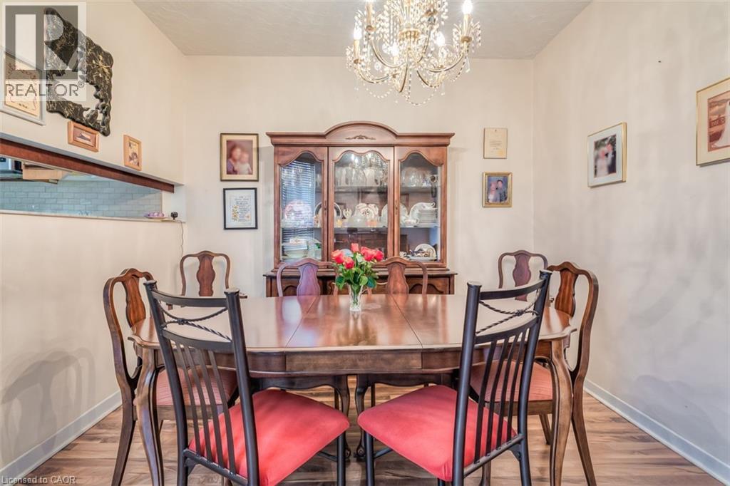Dining area featuring wood-finish flooring, a built-in crystal chandelier, and a pass-through window with a subway tile backsplash - 41 Springhurst Avenue, Toronto, ON