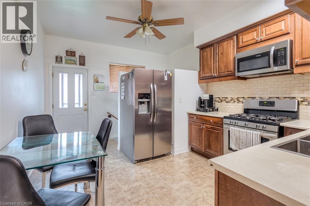 Kitchen featuring wood cabinetry, stainless steel appliances, a tile backsplash, and light-toned countertops - 41 Springhurst Avenue, Toronto, ON