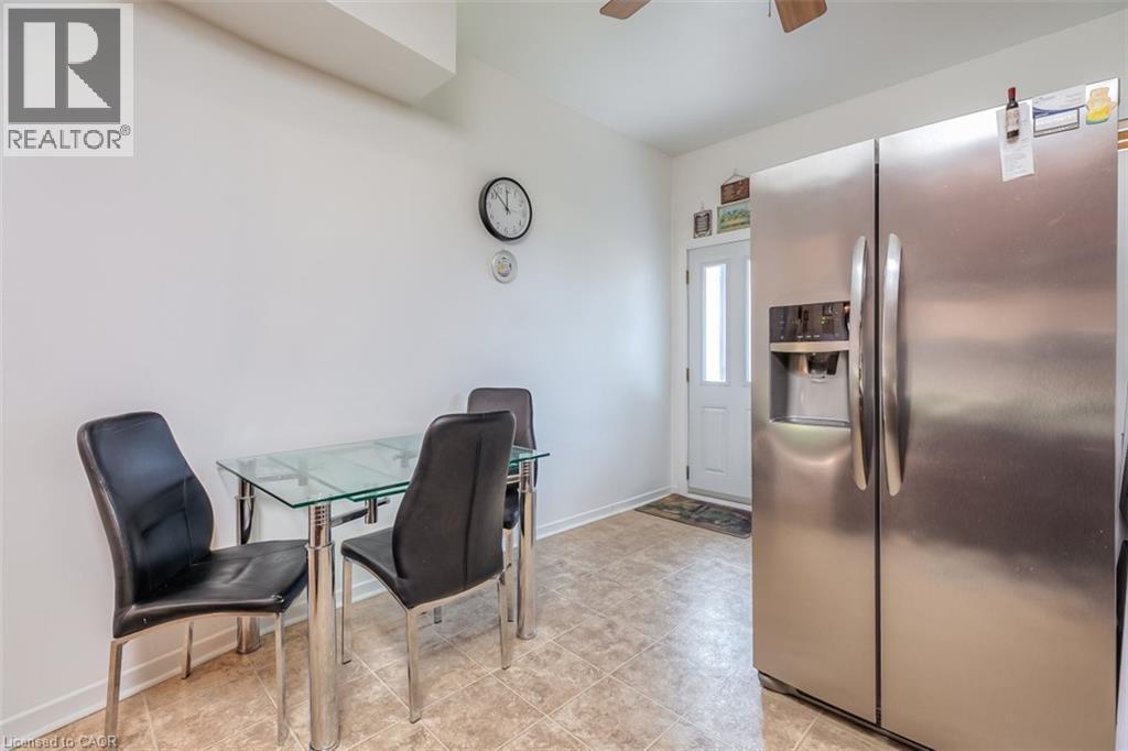 Kitchenette featuring neutral wall paint, light-toned tile flooring, a built-in stainless steel refrigerator with an ice and water dispenser, and a white paneled exterior door with a frosted glass ins - 41 Springhurst Avenue, Toronto, ON