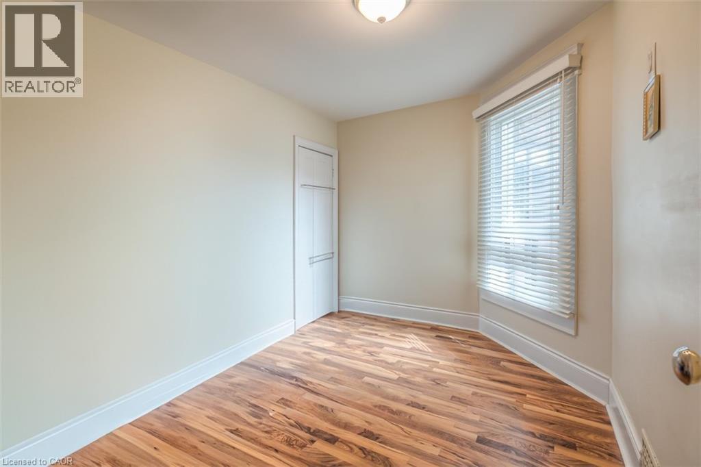 Room featuring wood-finish flooring, a bay window with blinds, a built-in closet with a paneled door, and a flush-mount ceiling light fixture - 41 Springhurst Avenue, Toronto, ON