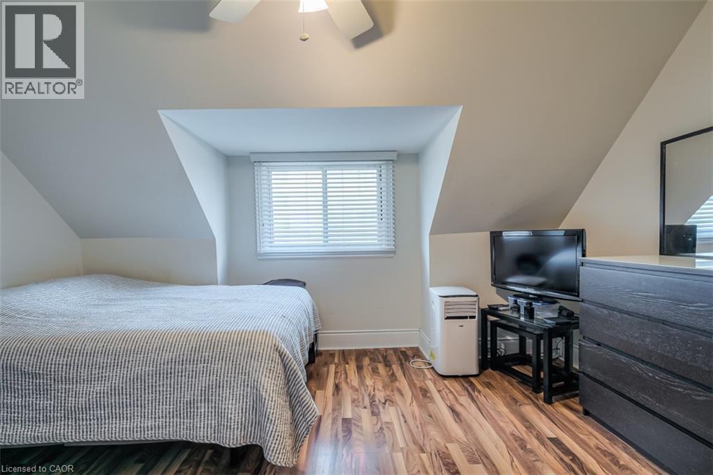 Attic room featuring sloped ceilings, wood-finish flooring, a window with horizontal blinds, and a ceiling fan - 41 Springhurst Avenue, Toronto, ON