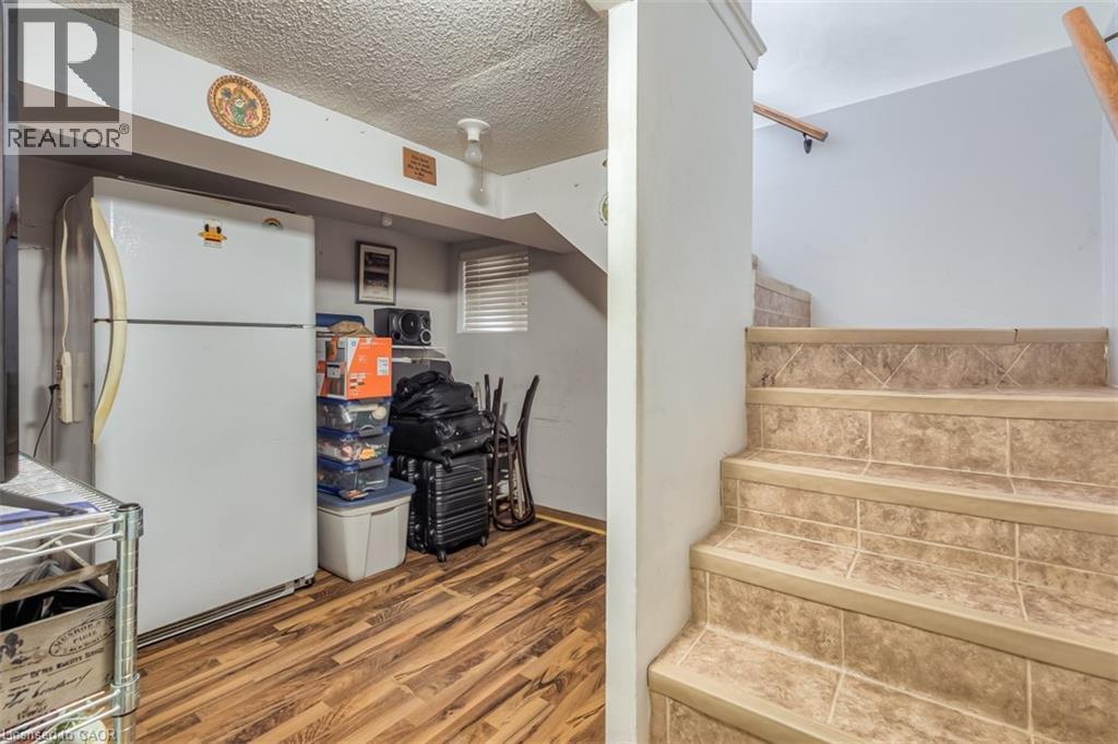 Tiled staircase with wood handrail, leading to an area with wood-finish flooring and a textured ceiling - 41 Springhurst Avenue, Toronto, ON