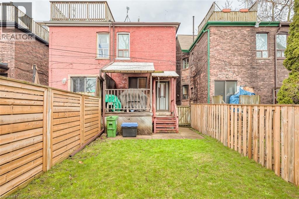 Expansive backyard featuring a green lawn, wood privacy fencing, and a raised wooden deck with stairs - 41 Springhurst Avenue, Toronto, ON