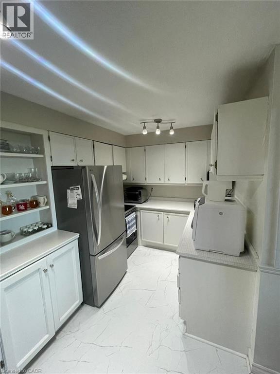 Kitchen featuring white cabinetry, light-toned countertops, and a full suite of stainless steel appliances - 225 Harvard Place Unit# 1505, Waterloo, ON