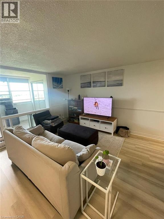 Open-concept living space featuring light wood-finish flooring and a neutral color palette - 225 Harvard Place Unit# 1505, Waterloo, ON