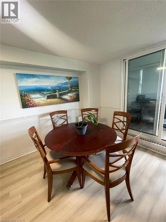 Dining area featuring light wood-finish flooring, white baseboards, and a chair rail molding - 225 Harvard Place Unit# 1505, Waterloo, ON