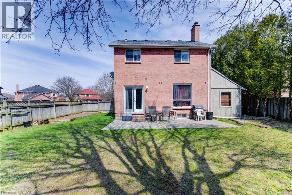 Brick exterior with a large patio area, double-door access, upper-level windows, a prominent chimney, and a fenced perimeter - 27 Tassie Lane, Cambridge, ON