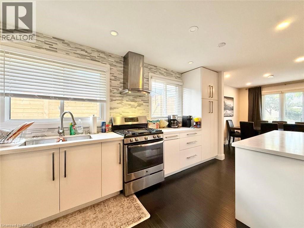 Modern kitchen featuring a stainless steel gas range, coordinating range hood, and crisp white cabinetry - 3135 Palmer Drive, Burlington, ON