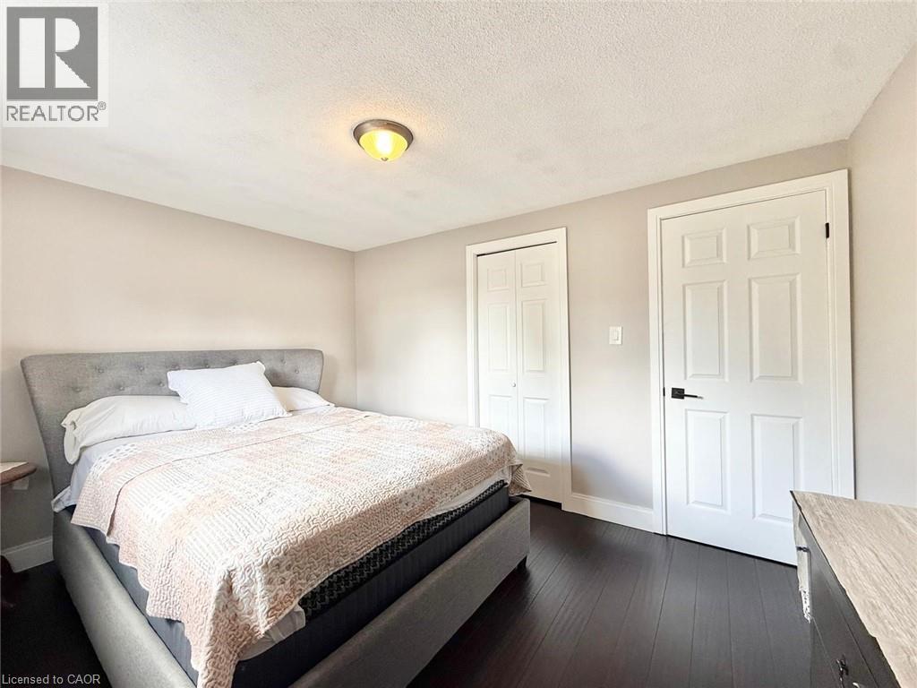 Bedroom featuring dark wood-finish flooring, light neutral wall paint, and white trim - 3135 Palmer Drive, Burlington, ON