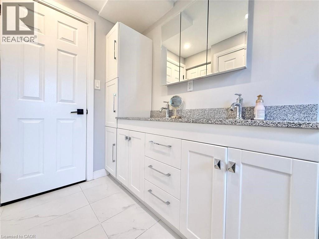 White shaker-style vanity with dual chrome faucets and granite countertop - 3135 Palmer Drive, Burlington, ON