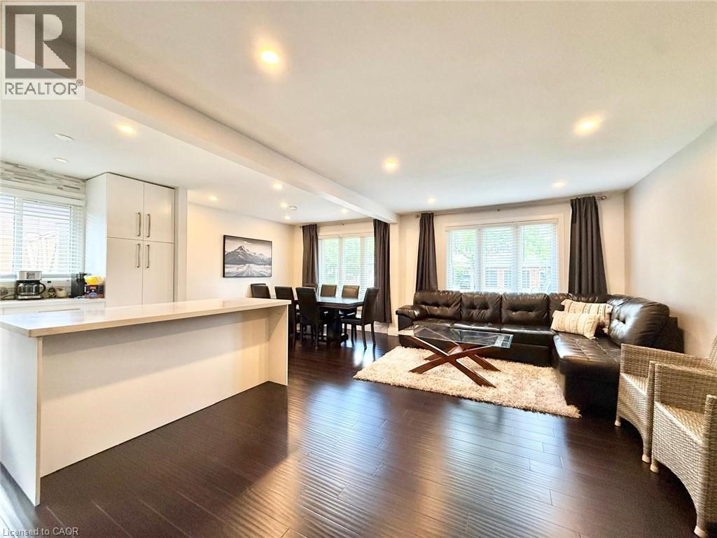 Open-concept living space featuring wood-finish flooring, recessed lighting, and a kitchen island with a light-toned countertop - 3135 Palmer Drive, Burlington, ON